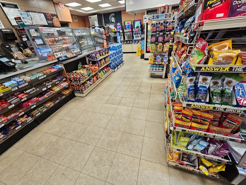 Convenience store interior with tiled aisles, snack displays, and checkout area